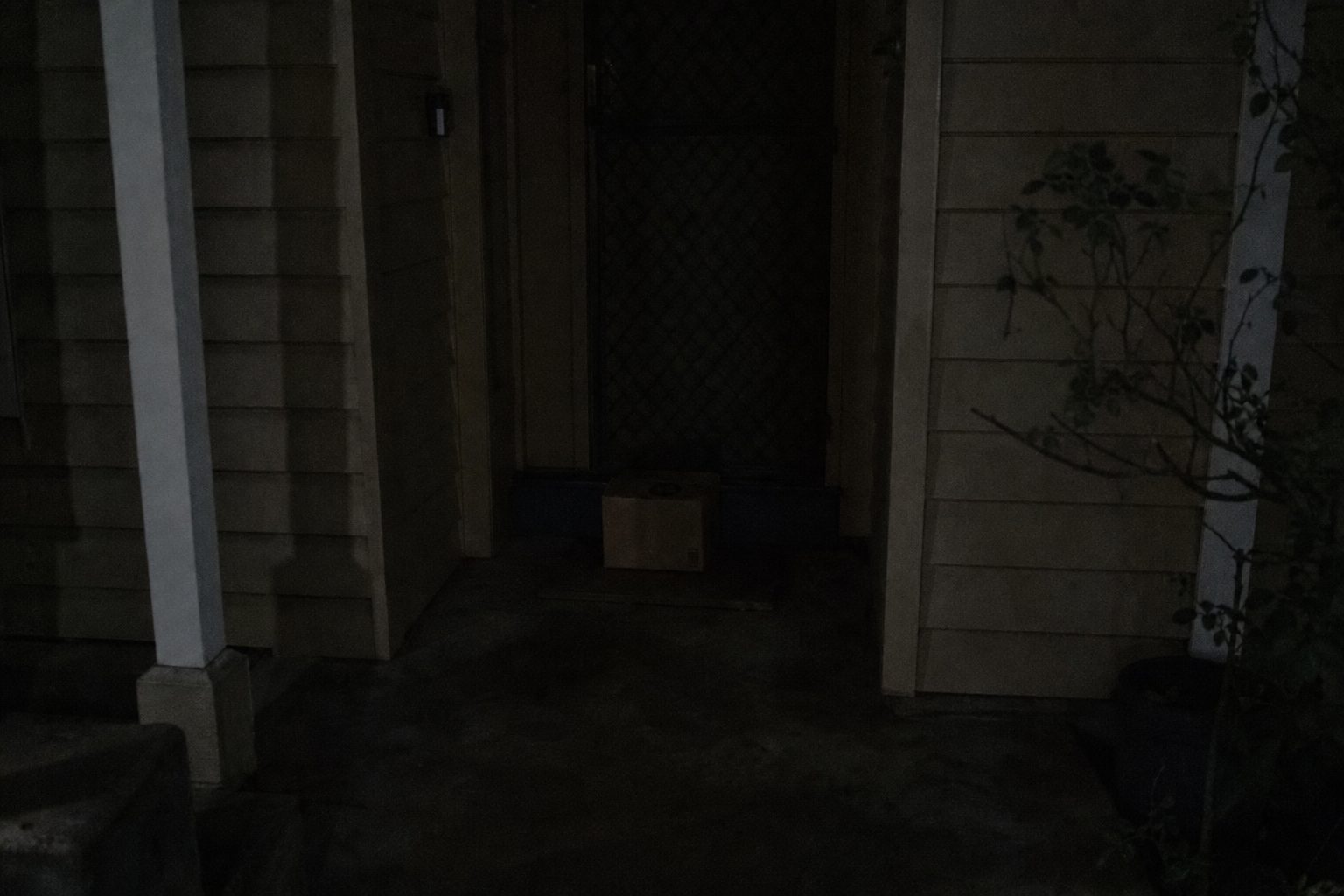 A dark front porch at night with a parcel on the step